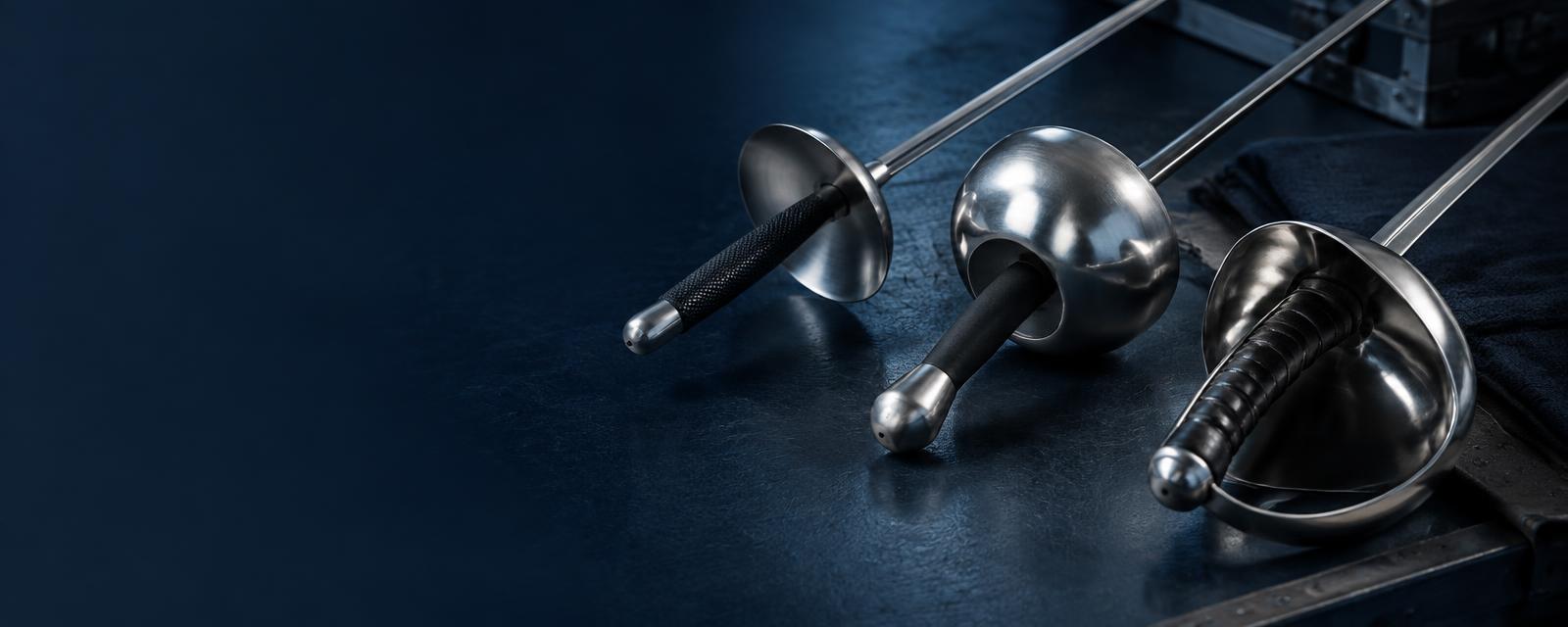 Foil, épée and sabre arranged on an armoury bench